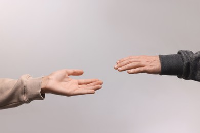 Photo of Man reaching for helping hand on light grey background, closeup