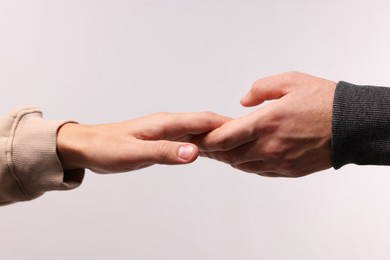 Photo of Help and support. People holding hands on light grey background, closeup