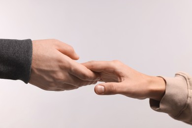 Photo of Help and support. People holding hands on light grey background, closeup