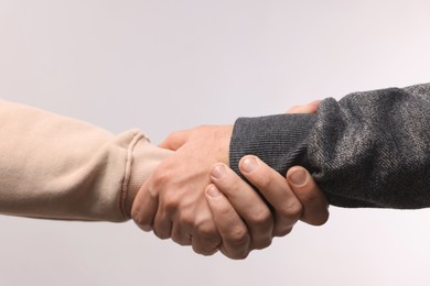 Photo of Help and support. People holding hands on light grey background, closeup