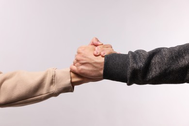 Photo of Help and support. People holding hands on light grey background, closeup