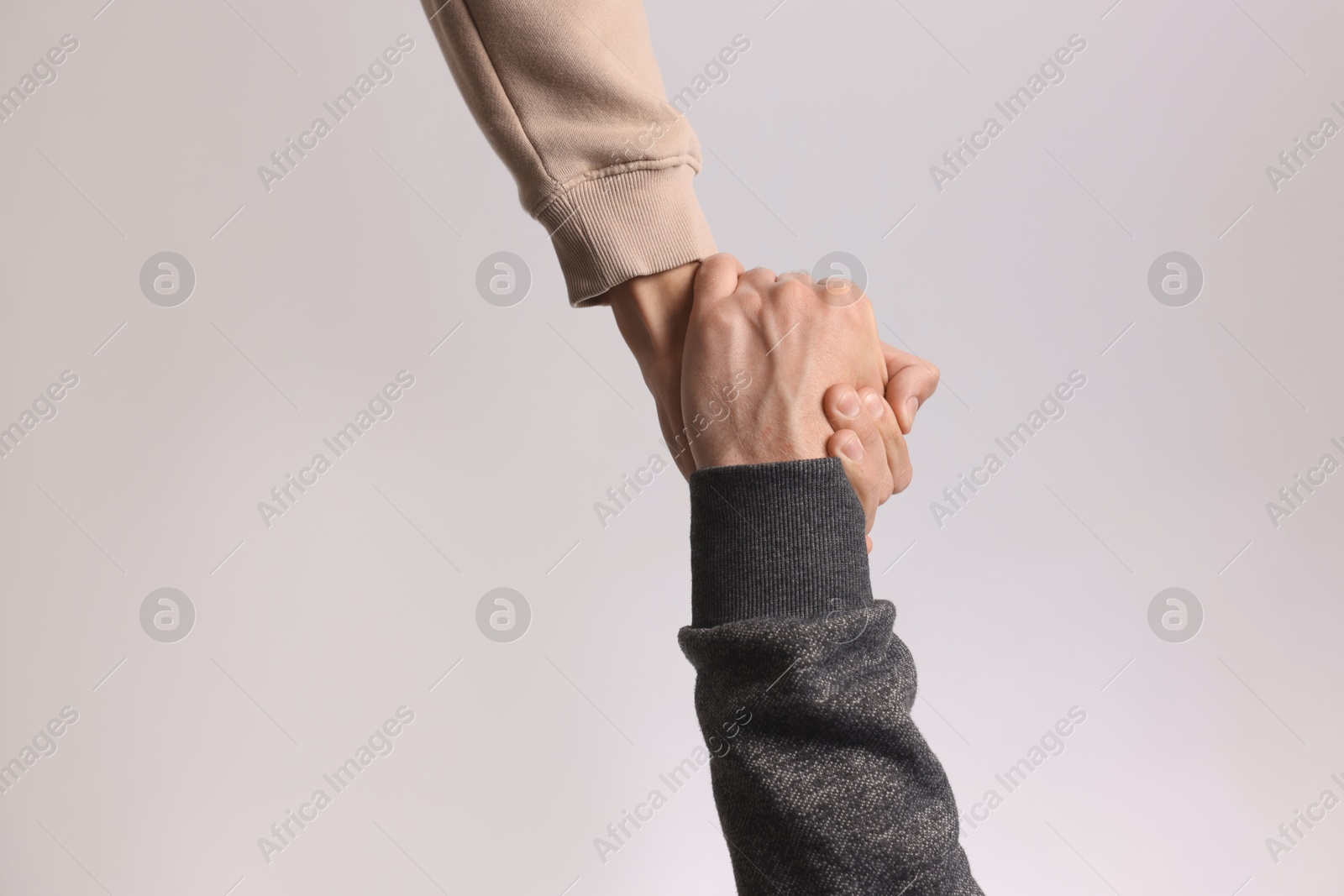 Photo of Help and support. People holding hands on light grey background, closeup