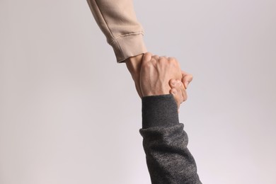 Photo of Help and support. People holding hands on light grey background, closeup