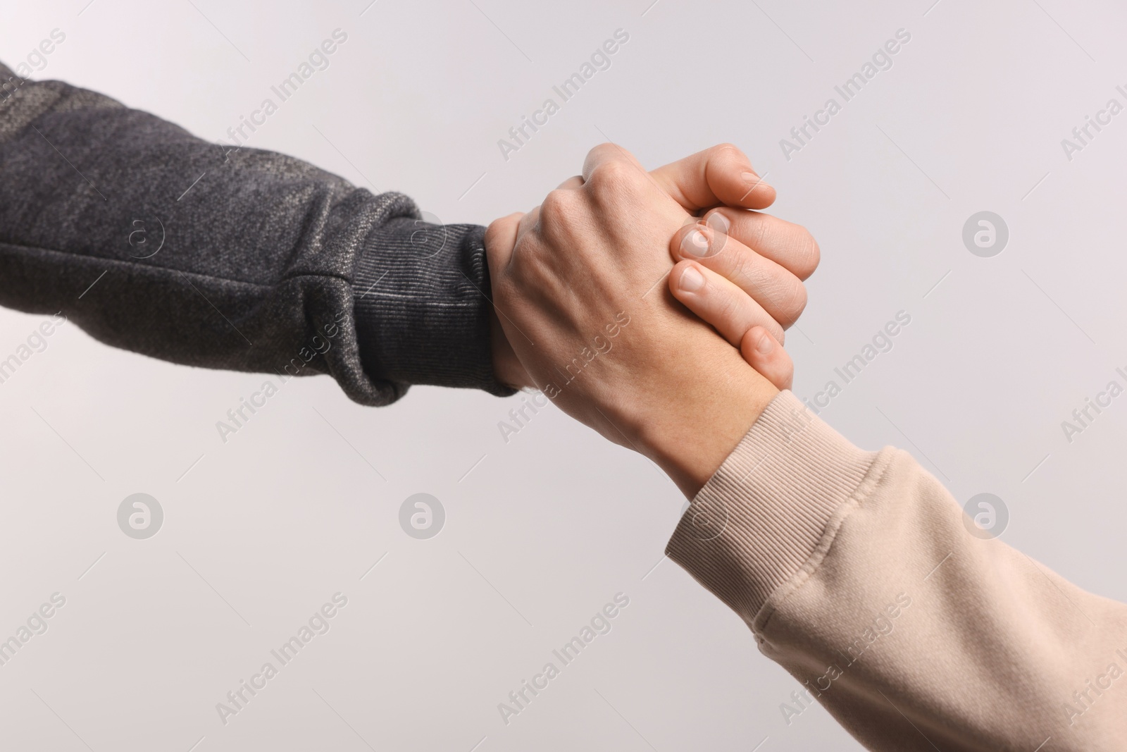 Photo of Help and support. People holding hands on light grey background, closeup