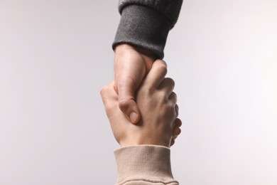 Photo of Help and support. People holding hands on light grey background, closeup