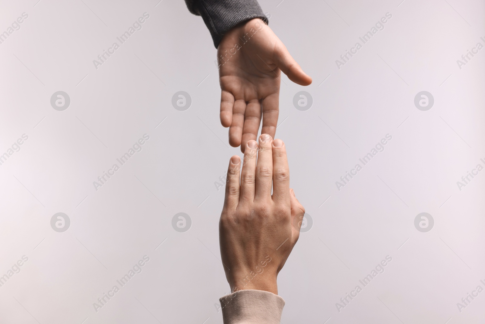 Photo of Man offering helping hand to his friend on light grey background, closeup