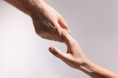 Photo of Help and support. People holding hands on light grey background, closeup