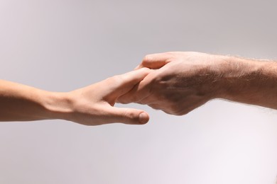 Photo of Help and support. People holding hands on light grey background, closeup