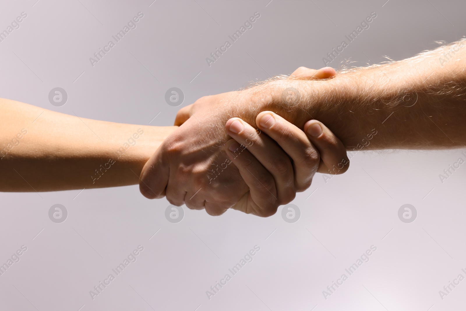 Photo of Help and support. People holding hands on light grey background, closeup