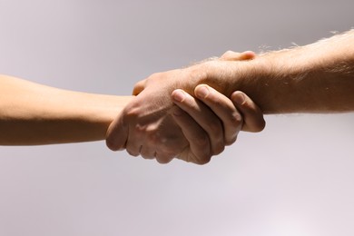 Photo of Help and support. People holding hands on light grey background, closeup