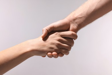 Help and support. People holding hands on light grey background, closeup