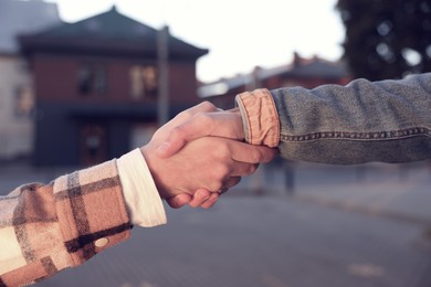 Help and support. People holding hands on city street, closeup