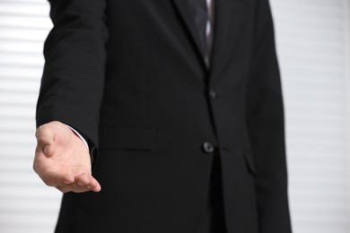 Photo of Man offering helping hand on light background, closeup