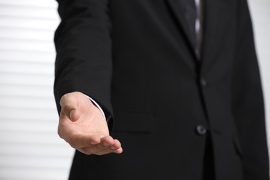 Man offering helping hand on light background, closeup