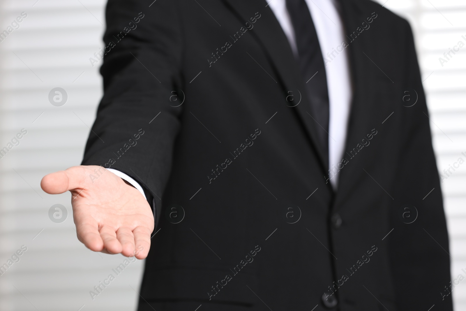 Photo of Man offering helping hand on light background, closeup