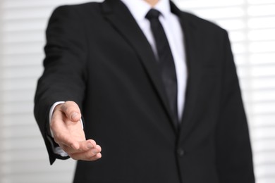 Man offering helping hand on light background, closeup