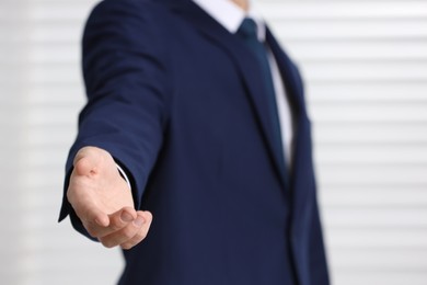 Photo of Man offering helping hand on light background, closeup