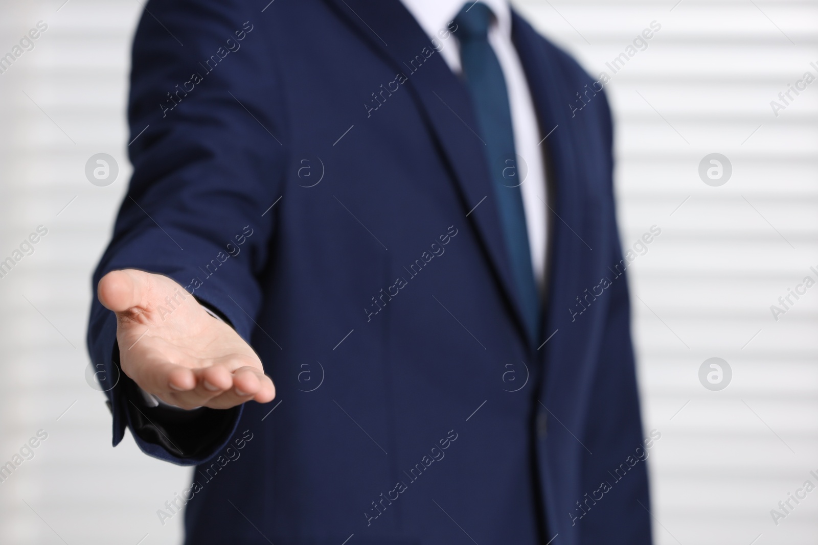 Photo of Man offering helping hand on light background, closeup