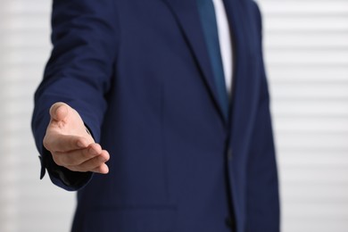 Man offering helping hand on light background, closeup