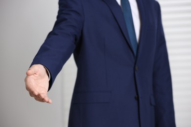 Photo of Man offering helping hand on light background, closeup