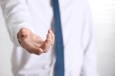 Man offering helping hand on light background, closeup