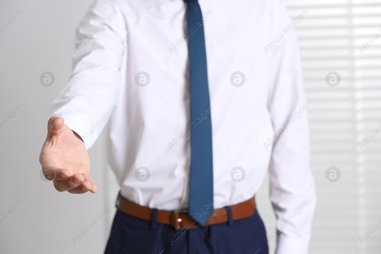 Photo of Man offering helping hand on light background, closeup