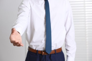 Man offering helping hand on light background, closeup