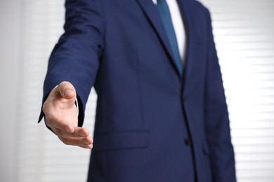 Man offering helping hand on light background, closeup