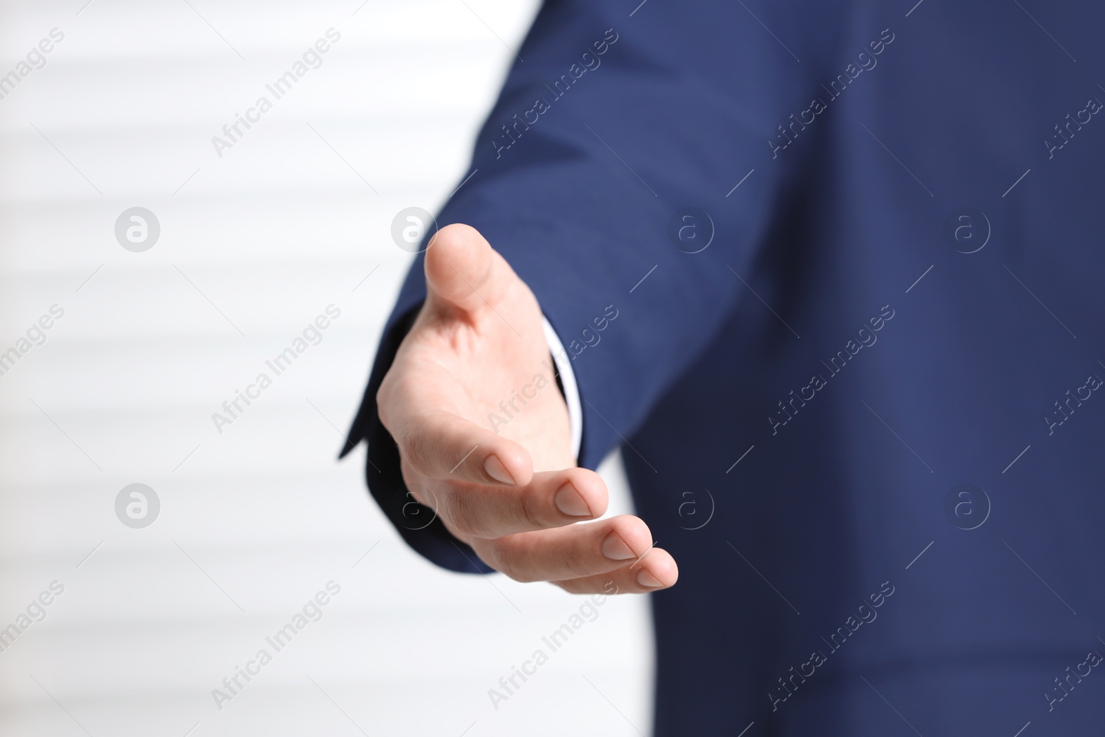 Photo of Man offering helping hand on light background, closeup