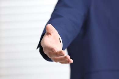 Man offering helping hand on light background, closeup