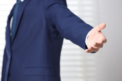 Photo of Man offering helping hand on light background, closeup