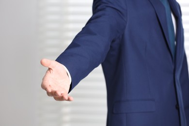 Photo of Man offering helping hand on light background, closeup