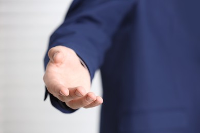 Man offering helping hand on light background, closeup