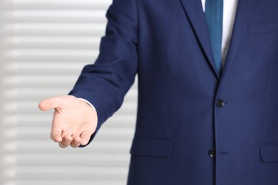 Photo of Man offering helping hand on light background, closeup