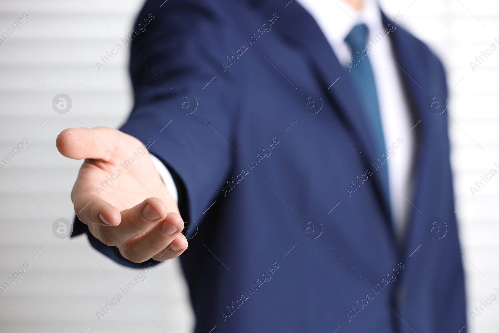 Photo of Man offering helping hand on light background, closeup