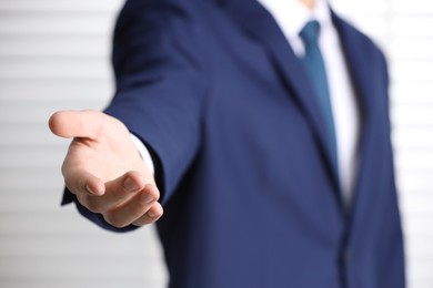 Photo of Man offering helping hand on light background, closeup