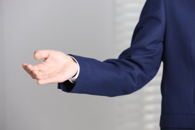 Man offering helping hand on light background, closeup