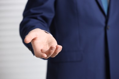 Man offering helping hand on light background, closeup