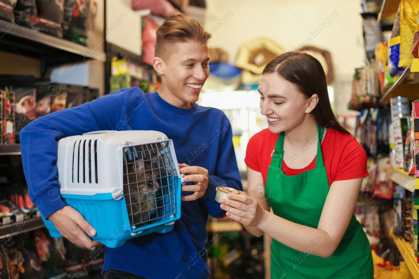 Photo of Pet shop worker recommending food for man's cute cat indoors