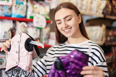 Woman choosing outfit for her dog in pet shop