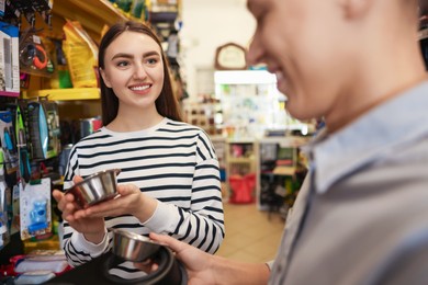 Man and woman choosing bowl in pet shop, selective focus