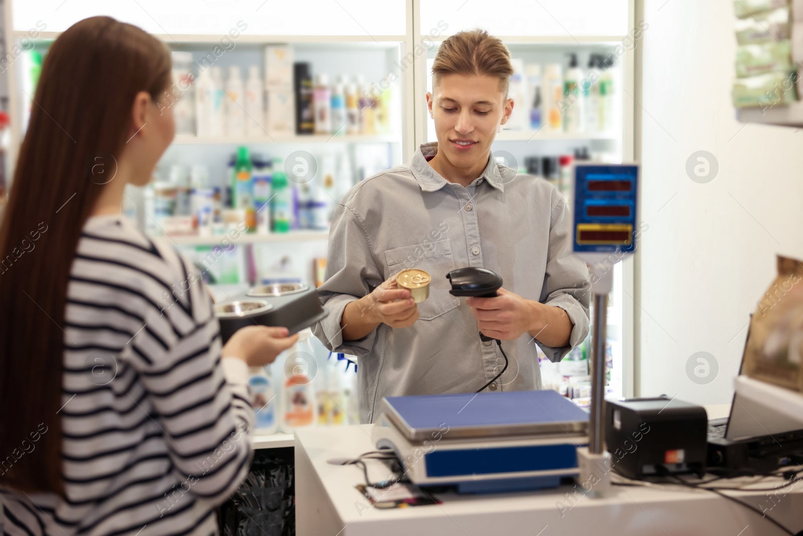 Photo of Cashier checking out woman's purchase in pet shop, selective focus