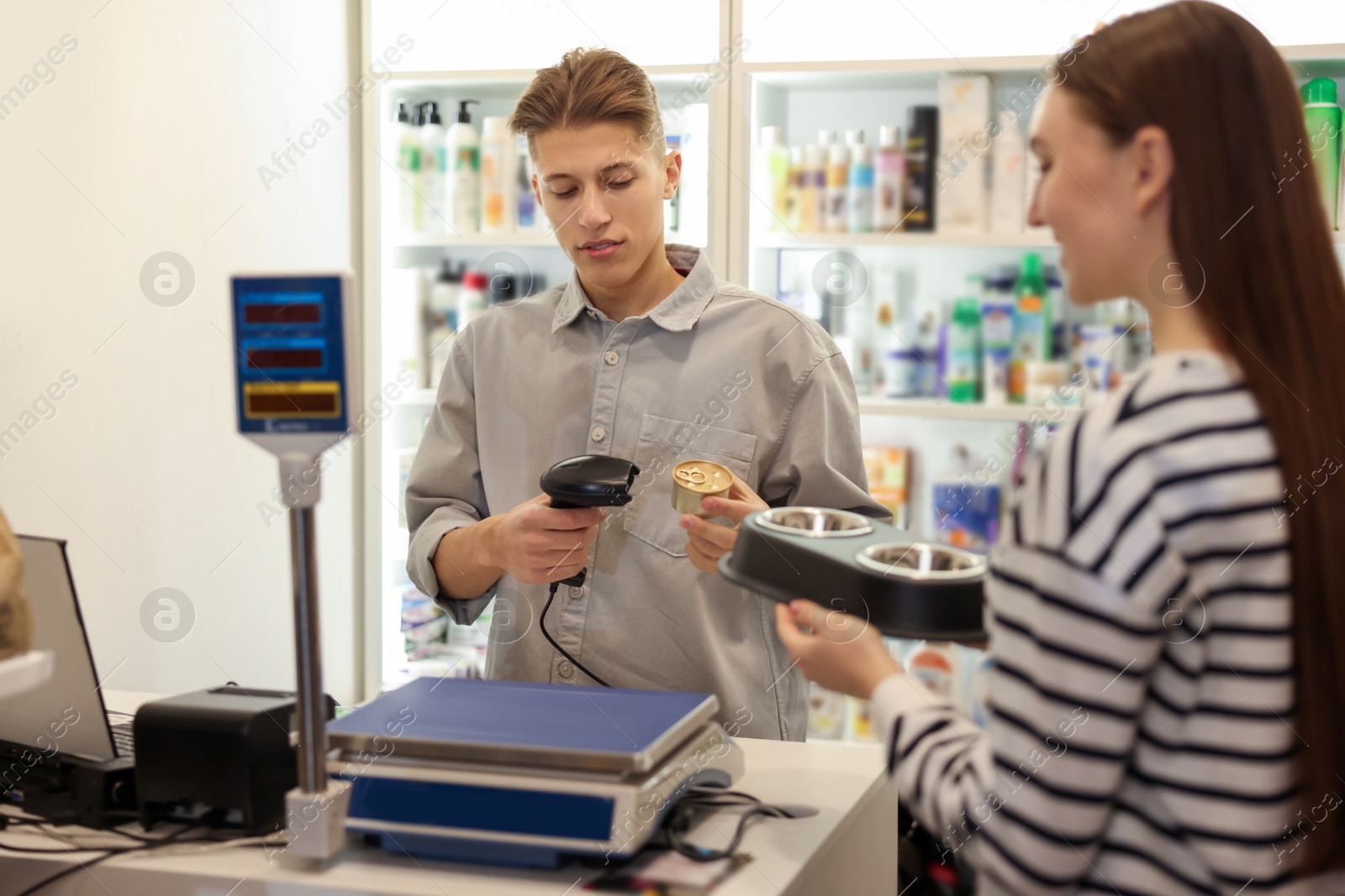 Photo of Cashier checking out woman's purchase in pet shop, selective focus