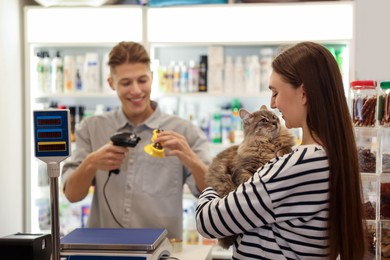 Photo of Woman buying toy for her cat in pet shop, selective focus