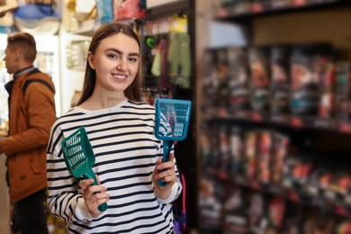 Smiling woman with litter scoops in pet shop