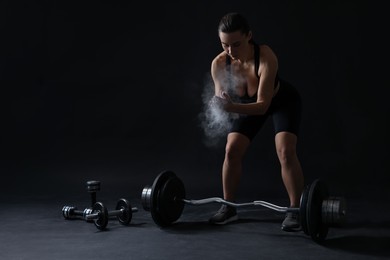 Photo of Woman clapping hands with talcum powder before training on black background. Space for text