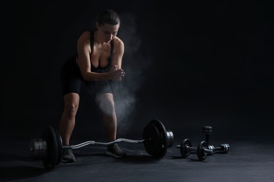 Photo of Woman clapping hands with talcum powder before training on black background. Space for text