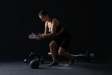 Photo of Woman clapping hands with talcum powder before training on black background