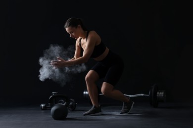 Photo of Woman clapping hands with talcum powder before training on black background