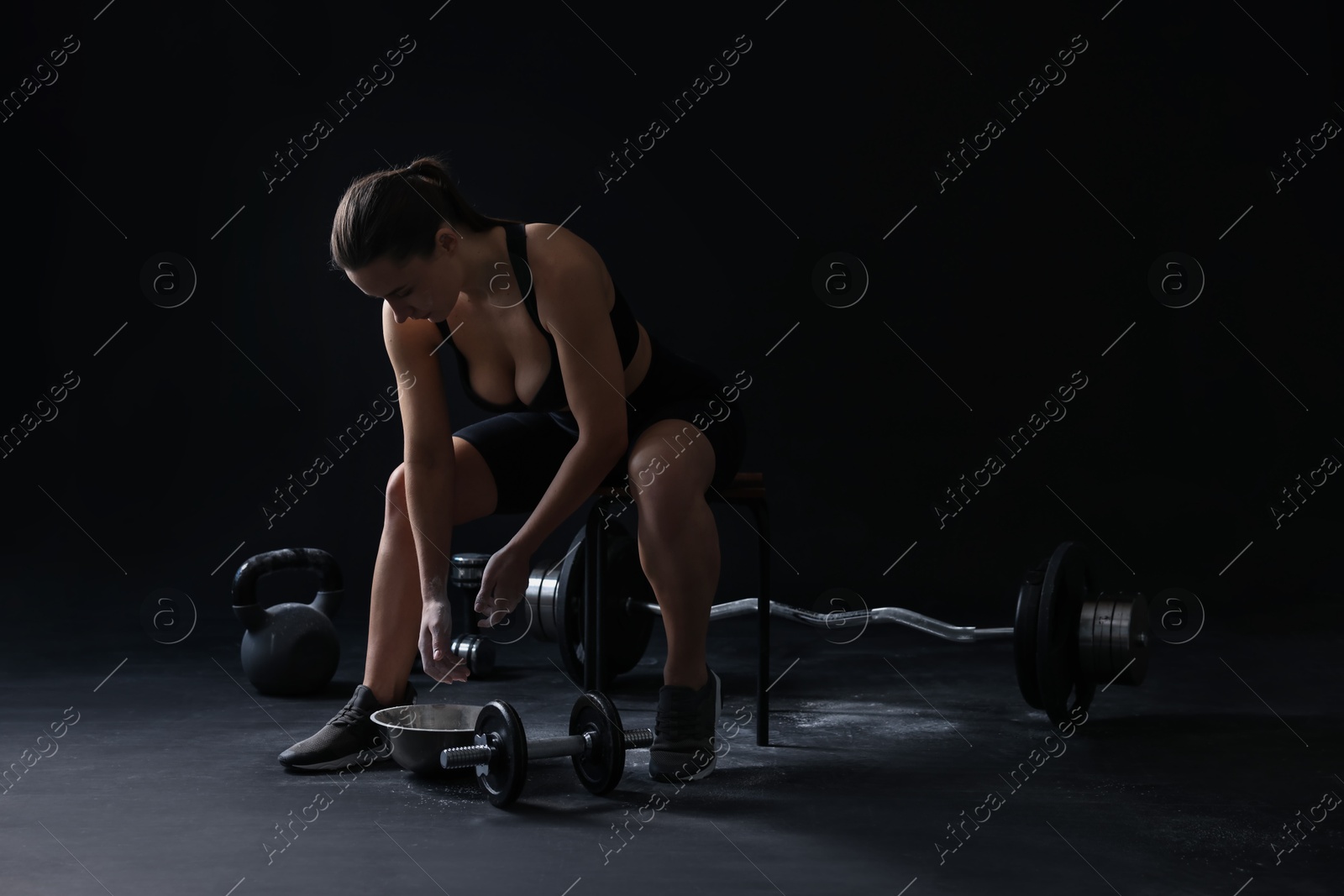 Photo of Woman applying talcum powder onto hands before training on black background